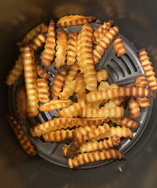 imagine deasupra capului a coșului de gătit al friteuzei ninja air max xl care conține niște cartofi prăjiți aurii și niște cartofi prăjiți.